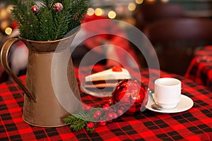 Cup of coffee and christmas toy on wooden table. A copper jug Ã¢â¬â¹Ã¢â¬â¹and fir branches stand on table.